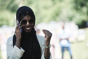 afrikansk kvinna använder sig av smartphone bär traditionell islamic kläder foto
