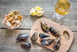 musslor med ett glas vin på träbordet foto