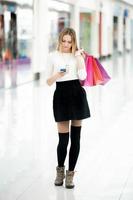 vacker tonårsflicka tittar på mobiltelefonen i shoppingcente foto