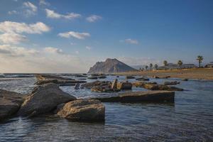 lång exponering fotografi av vågor och småsten på strand i de solnedgång foto