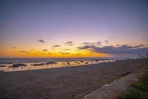 lång exponering fotografi av vågor och småsten på strand i de solnedgång foto
