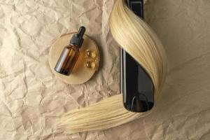 en hår behandling grundläggande olja för glättning hår och en hår glättning järn liggande på en brun hantverk papper bakgrund foto