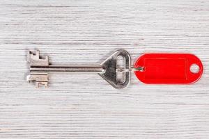 stor dörr nyckel med röd Nyckelring på trä- tabell foto