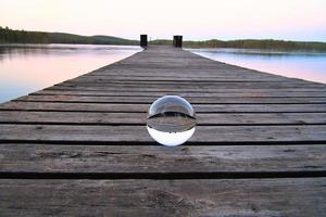 glas boll på en trä- pir på en svenska sjö på kväll timme. natur skandinavien foto