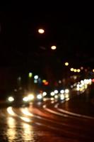 suddig natt scen av trafik på de körbana. defocused bild av bilar reser med lysande strålkastare. bokeh konst foto