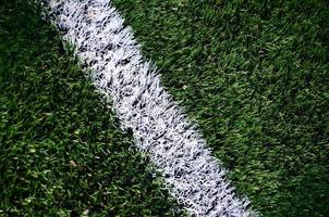 vit rand på en ljus grön artificiell gräs fotboll fält foto