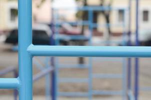 blå metall rör och tvärstänger mot en gata sporter fält för Träning i friidrott. utomhus- atletisk Gym Utrustning. makro Foto med selektiv fokus och ytterst suddig bakgrund