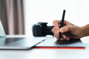 grafisk designer eller fotograf använda sig av penna mus teckning och retuschera på en läsplatta styrelse. foto
