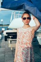 blond tjej i blommaklänning och solglasögon som håller båt segel foto