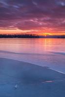 färgglad vinter solnedgång över en frusen sjö foto