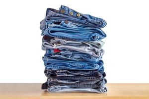 denim blå jeans stack på trä tabell isolerat på vit bakgrund foto