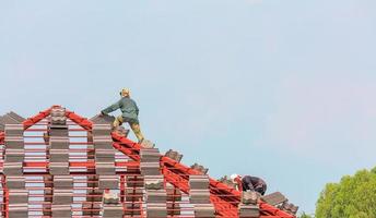 byggtäckare som installerar takpannor på husbyggarbetsplatsen foto