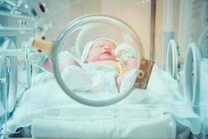 nyfödd bebis inuti inkubator i sjukhus posta leverans rum foto