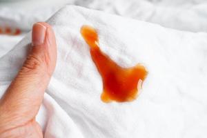 smutsig tomat sås färga eller ketchup på trasa till tvätta med tvättning pulver, rengöring hushållsarbete begrepp. foto