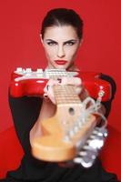 konstnärlig kvinna på röd bakgrund med elgitarr foto