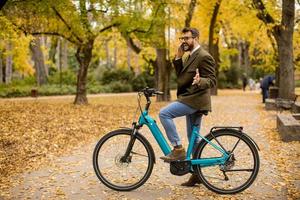 ung man med elektrisk cykel i höstparken foto