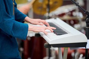 musiker kvinna spelar på synthesizer tangentbord piano, händer tryck synthesizer tangenter på konsertscenen foto