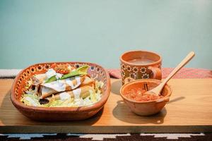 mexikansk flautas med sallad, avokado, grädde, sås och färsk vatten foto