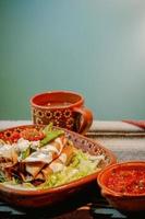 mexikansk flautas med sallad, avokado, grädde, sås och färsk vatten foto