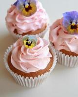 hemlagad rosa frosting vaniljmuffin med ätliga blommor foto