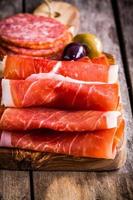 tunna skivor av prosciutto med salami på en skärbräda foto