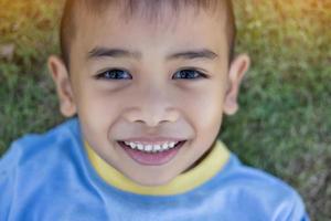 glad mulatt pojke barn ler och njuter av adoptivlivet. porträtt av ung pojke i naturen, parken eller utomhus. begreppet lycklig familj eller framgångsrik adoption eller föräldraskap. foto