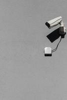 små vit övervakning kamera på platt grå matt plåster vägg foto
