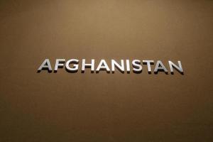 de ord afghanistan lagd med silver- metall brev på grov solbränna kaki duk tyg foto