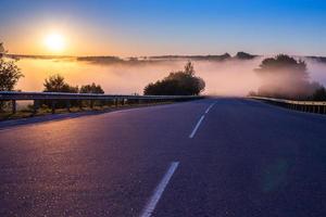 dance tidigt morgon- dimma i wold på sommar motorväg nära flod med vakt skenor foto