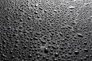 närbild se av vatten droppar på svart hydrofob yta makro sith selektiv cous och bakgrund fläck foto