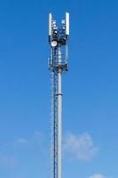 grå rör telekommunikation torn på blå himmel bakgrund, vertikal skott. foto