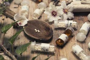 flaskor med homeopatikulor och sked foto