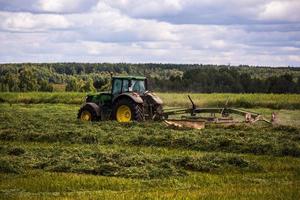 tula, ryssland juli 30, 2019 grön slåtter traktor på sommar fält innan storm - tele skott med selektiv fokus foto