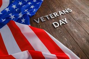 de ord veteraner dag lagd med silver- metall brev på trä- styrelse yta med skrynkliga USA flagga foto