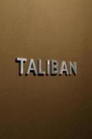 de ord taliban lagd med silver- metall brev på grov solbränna kaki duk tyg foto