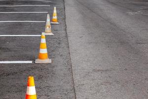 orange väg koner på en asfalt körning område med vit rader foto