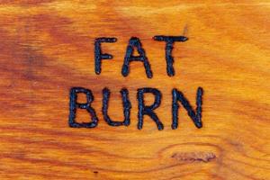 de ord fett bränna handskriven på trä- yta med vedbrännare foto
