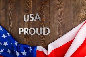 ord USA stolt lagd med silver- metall brev på brun trä- yta med flagga av förenad stater av Amerika foto