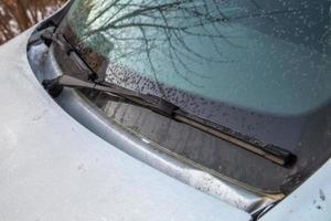 ljus frost flingor på morgon- bil vindskydd och vattenblad vindrutetorkare foto