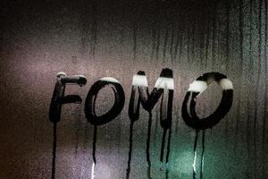 ord fomo - rädsla av saknas ut - handskriven på natt våt fönster glas yta foto