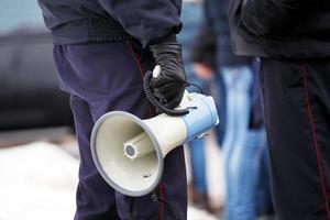 polis officer innehav högtalare megafon utomhus, närbild foto