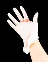 bruten vit latex kirurg medicinsk handske på caucasian hand isolerat på svart bakgrund foto