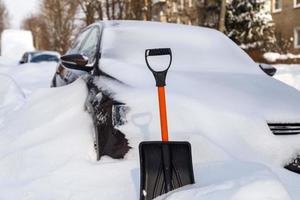 plast snö skyffel i främre av snötäckt bil på solig vinter- morgon- foto