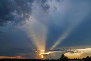 molnig solnedgång himmel med gul Sol strålar utan horisont foto