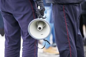 polis officer innehav högtalare megafon utomhus, närbild foto