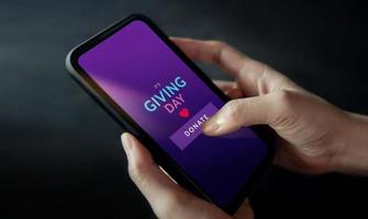 uppkopplad donation, välgörenhet och volontär begrepp. närbild av hand använder sig av en mobil telefon till framställning donera via de internet foto