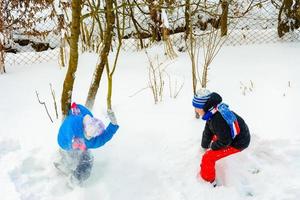 två Pojkar spela snöbollar, en roligt spel under de vinter, en Lycklig barndom för barn. foto