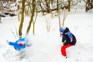 två Pojkar spela snöbollar, en roligt spel under de vinter, en Lycklig barndom för barn. foto