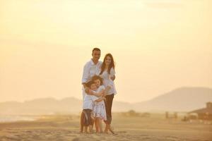 Lycklig ung familj ha roligt på strand på solnedgång foto