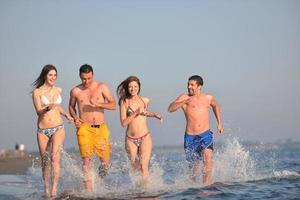 Lycklig människor grupp ha roligt och löpning på strand foto
